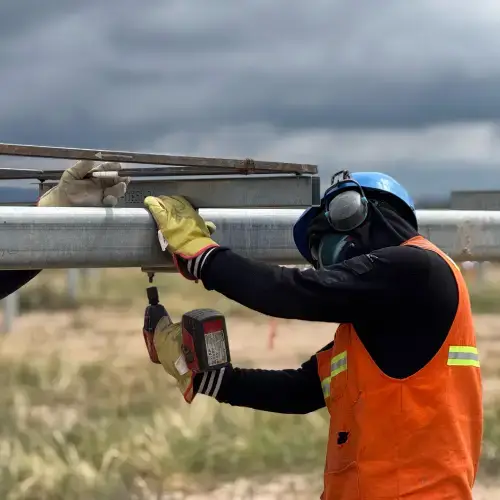 trabajador atornillando tubo con atornillador electrico y elementos de seguridad